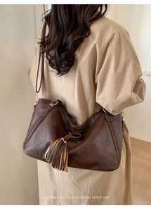 Detail of dark brown leather tote featuring woven edge stitching and stylish tassels
