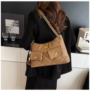 Detail of a brown quilted leather shoulder bag with gold chain strap worn by a model