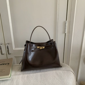 Detail of the golden metal lock and buckle on a vintage dark brown bucket bag