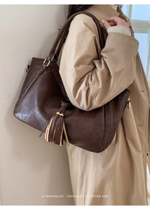 Detail of dark brown retro leather tote with woven texture and tassel accessory