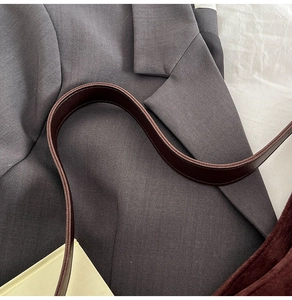 Detailed close-up of dark brown leather bag strap with precise hand-stitched stitching