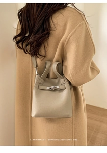 Close-up of a minimalist leather handbag with metal turn-lock and lychee grain texture