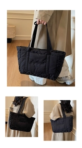 Macro shot of black quilted tote bag featuring elegant embroidery and plush textures