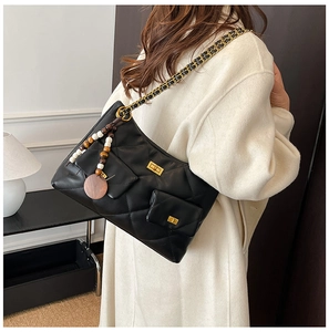 Détail du sac bandoulière matelassé noir avec chaîne dorée et pendentif rétro en bois