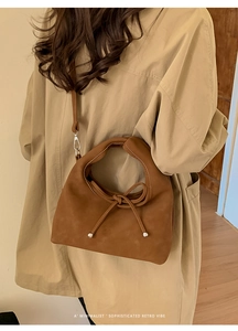Brown vintage suede handbag with bow detail and thin strap worn with a beige trench coat