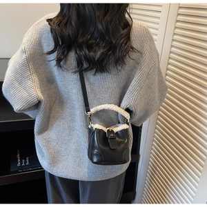 Détail du mini sac seau noir avec bordure en laine d'agneau et boucle en métal sur sangle