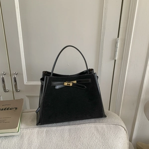 Detail of a vintage black bucket bag with gold lock hardware on a soft sofa