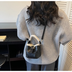 Détail du mini sac seau en cuir noir avec bordure en fausse fourrure blanche douce