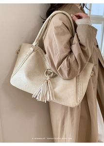 Detail showing retro tassel charm and woven leather stitching on this large beige tote bag
