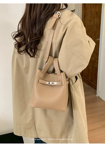 Detail of beige lychee grain leather bucket bag with metal clasp and adjustable strap