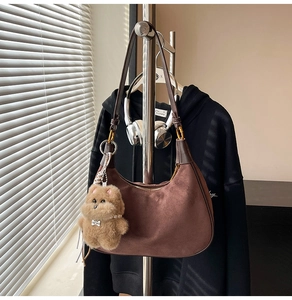 Detail der kaffeebraunen Wildleder-Hobo-Tasche mit Bärenanhänger und Perlenkette