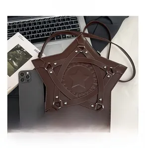 Star-shaped dark brown crossbody bag with silver rivets and embossing on a desk
