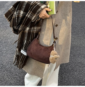 Detail der dunkelbraunen Wildleder-Hobotasche mit Teddybär-Anhänger und Herbstoutfit