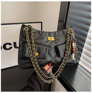 Détail du sac matelassé noir avec bandoulières en chaîne dorée et pompon en perles de bois