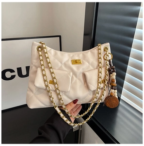 Détail du sac matelassé crème avec fermoirs dorés et pompon perlé de style bohème