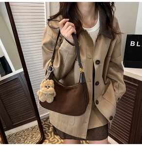 Detailed view of vintage brown suede crescent bag with dark leather trim and plush bear charm