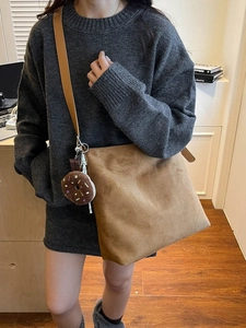 Brown suede tote bag with leather strap and fun charms shown on a casual sweater