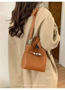 Brown litchi leather bucket bag shown on a model wearing a stylish khaki trench coat