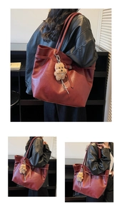 Detail of burgundy vintage tote bag with plush puppy charm and adjustable side strap