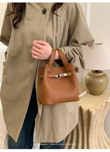 Detailed view of brown lychee grain leather bucket bag with silver metal buckle strap