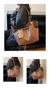 Detail view of large brown tote bag with leather buckle and cute plush teddy bear charm