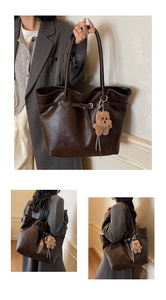 Detail of dark brown tote bag with leather texture and cute teddy bear charm