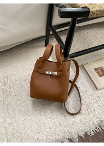 Detailed close-up of brown litchi pattern leather bucket bag with silver metal lock