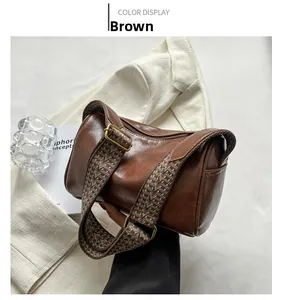 Détail du sac polochon en cuir marron avec boucle dorée et bandoulière tissée ethnique