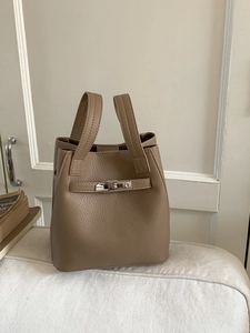 Chic taupe pebbled leather bucket bag with silver metal buckle and dual handles