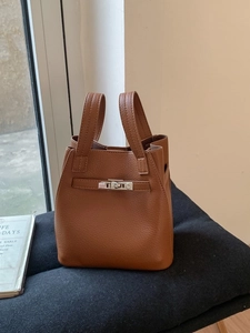 Brown lychee leather bucket handbag with metal turn-lock and retro minimalist design