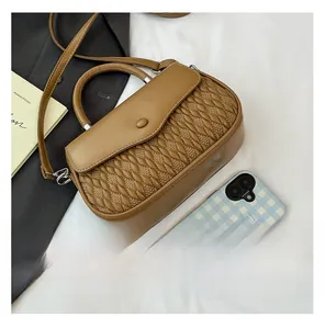 Close-up of brown leather bag with quilted embroidery and top handle on a white surface