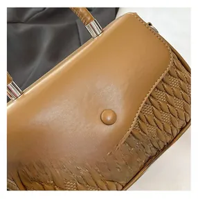 Detailed close-up of brown leather handbag featuring intricate side woven textures