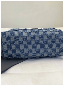 Detail of blue and white checkered denim tote bag featuring frayed tassel edges