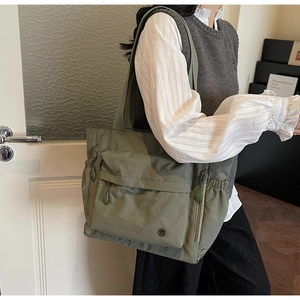 Detail view of army green nylon tote bag featuring functional elastic side pockets and logo