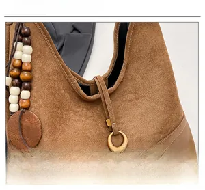 Detail of brown suede tote bag featuring wooden bead charms and metallic ring accents