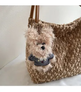 Détail d'un ours en peluche avec pull marine sur un sac cabas marron tressé