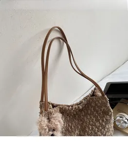 Détail d'un sac fourre-tout en peluche marron avec anses en cuir et breloque ours rose
