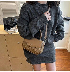 Detail of khaki crossbody bag with woven texture on model in a cozy office setting