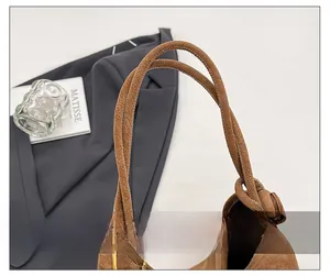 Detailed close-up of brown suede shoulder bag featuring minimalist knotted strap design