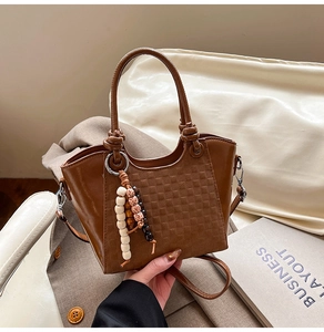 Detailansicht braune Eimertasche mit Karoprägung und dekorativem Holzperlenanhänger