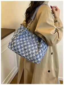 Detail of blue checkerboard denim tote bag with frayed edges and silver chain strap