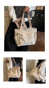 Detail der cremeweißen Tragetasche mit mehreren Taschen und breiten Stoffträgern