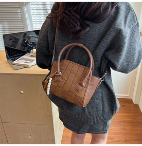 Close-up of brown woven checkered texture on handbag with beaded pendant and top handle