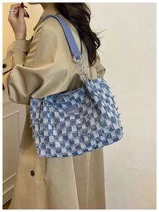 Detail of blue checkerboard tote bag with fringe edges and durable leather straps
