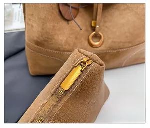 Close-up of suede shoulder bag featuring smooth gold metal zipper and hardware