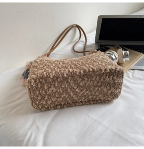 Nahaufnahme einer braunen Fleece-Tasche mit strukturiertem Stoff und kleinem Bär-Anhänger