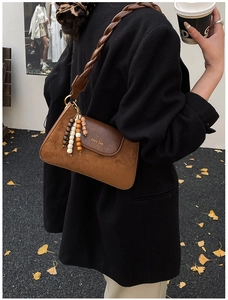 Detail of vintage brown suede shoulder bag with woven strap and beaded tassel charm