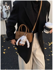 Detail of dark brown faux leather square bag with a cute plush rabbit pendant and strap