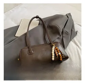 Detail of vintage dark brown faux leather shoulder bag with beaded fringe charm