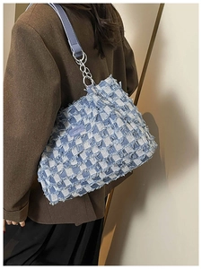 Detail of blue checkerboard tote bag featuring frayed edges and metal chain strap